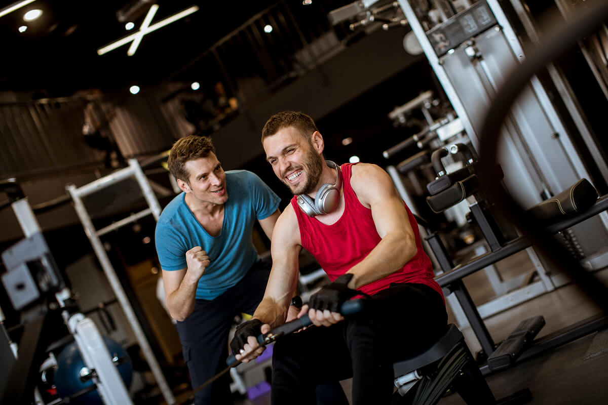 young-man-with-trainer-doing-exercise-in-the-gym-TETHN6F
